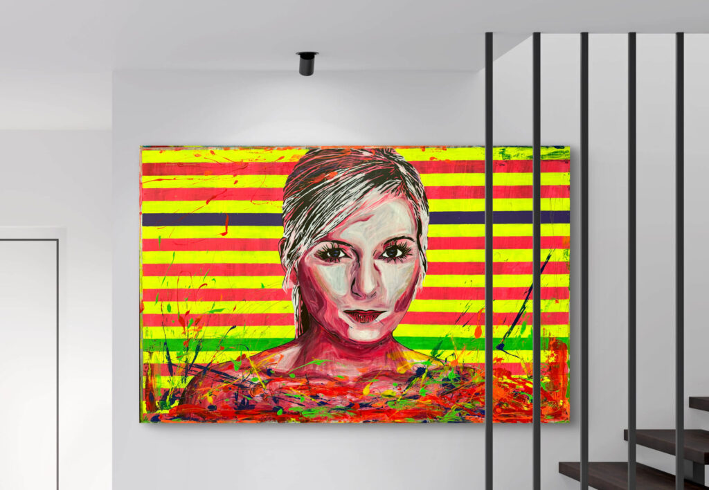 A colorful portrait painting is displayed on a wall. The artwork features a stylized woman's face with vibrant reds, pinks, and whites, set against bold horizontal stripes of yellow, red, and blue. The background has splashes of color, adding to the dynamic feel. A staircase and wall are partially visible in the surroundings.